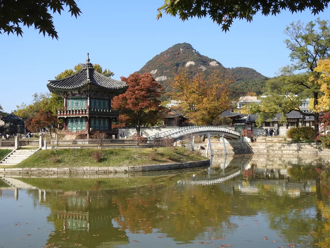Hyangwonjeong, a two-story pavilion on a pond in Gyeongbokgung, with a small bridge and autumn trees