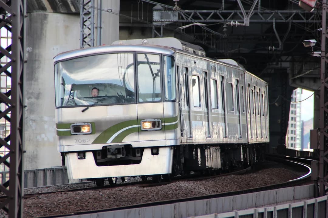 A silver and green Seoul Metro train curving along an elevated track