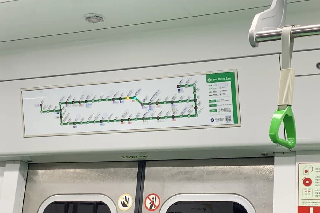 Route map of Line 2 shown above the doors inside a train, with the green loop line and a green grab handle in front