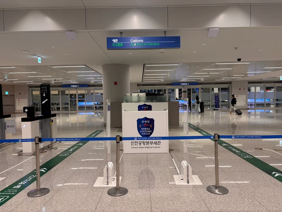 A Korea Customs Service counter with queue posts and a customs sign in an airport hall