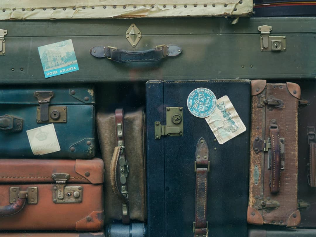 A stack of old leather suitcases with travel labels on them